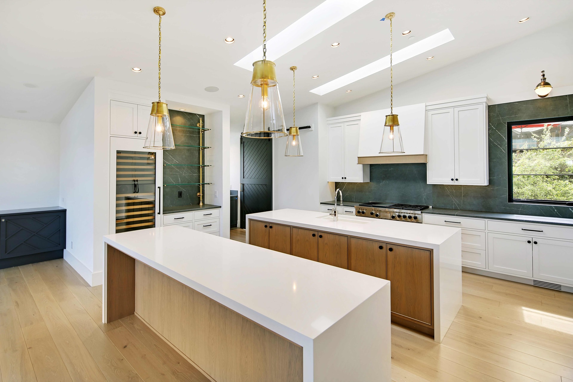 Luxury kitchen design by ID by Gwen featuring white cabinetry, dual islands, green marble backsplash, and brass pendant lighting in Mercer Island home